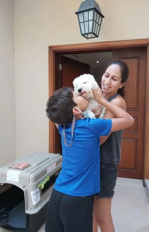 Mother and child cuddling their white dog at home